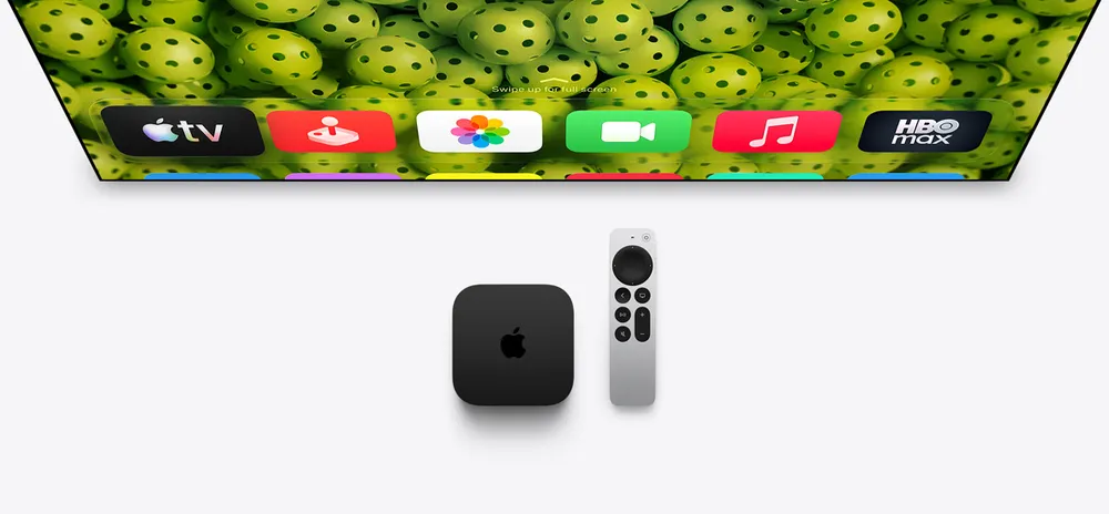 Apple TV 4K a ovladač Apple TV Remote pod televizí s řadou aplikací na obrazovce